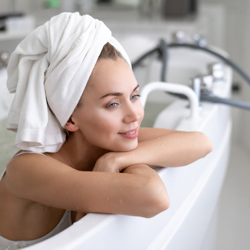 Woman with a towel wrapped around her head in a bathroom